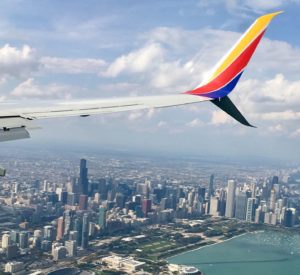 The Chicago skyline appears behind the wing of an airplane