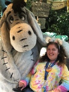 A girl posing with the character Eeyore at Disneyland.