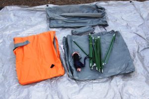 The items to build a tent include poles and tarp are laid out.