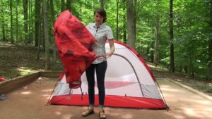 Woman prepares to put a rain tarp over her tent