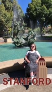 A girl in a black and white dress posing in front of a fountain at Stanford University.